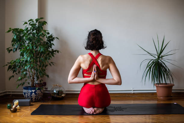 Young woman in Namaste behind the back